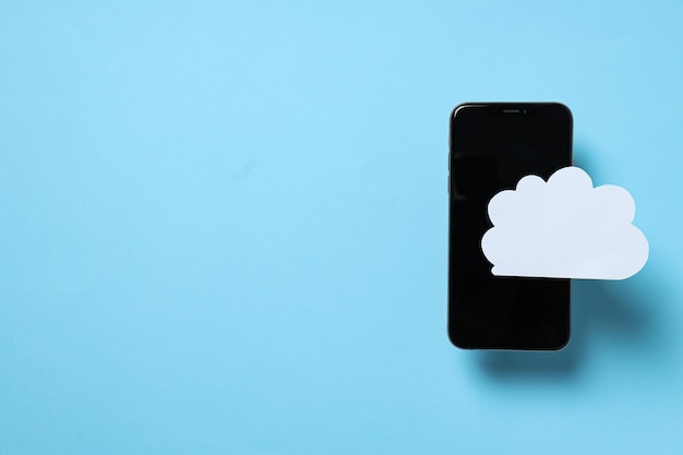 Black smartphone with a paper cloud on a blue background place for text