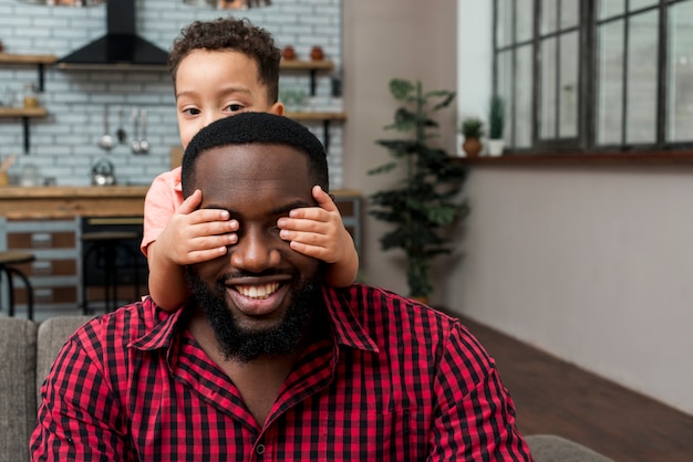 Black son covering eyes of father 