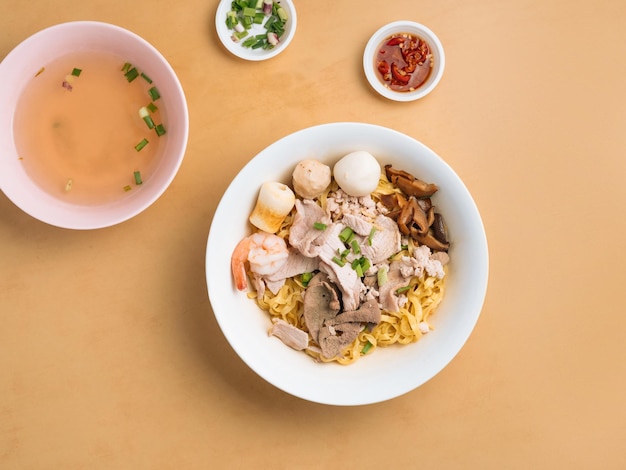 Black Soya Sauce Noodle in a bowl with soup chili sauce and spring onion top view on wooden table