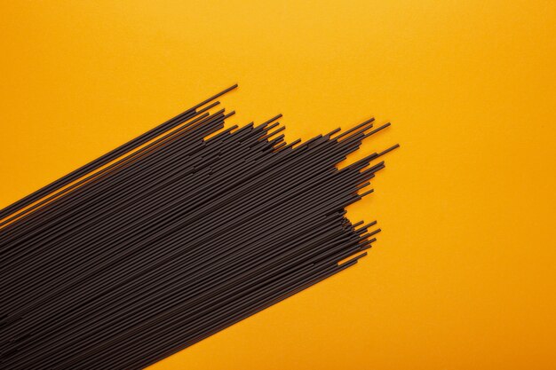 Black spaghetti on a yellow background