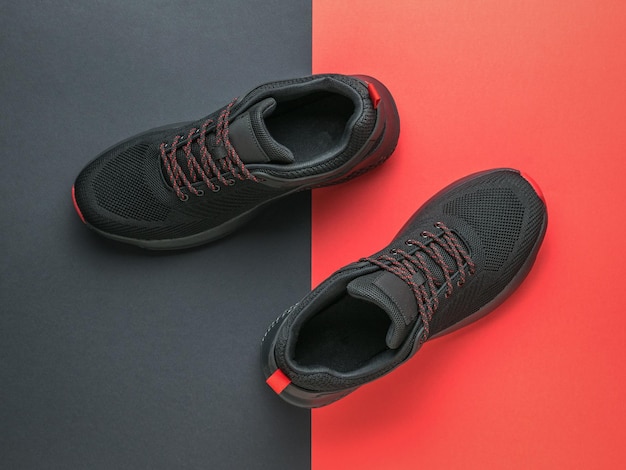 Black sports sneakers with red laces on a black and red background Minimal sports concept