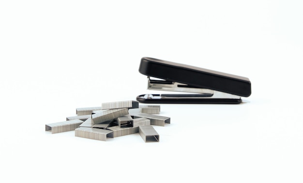 Black stapler and metal staple isolated on a white wall. Office Equipment and Work Tool concept Design.