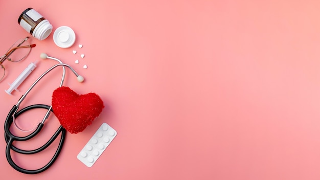 Black stethoscope with red heart and medicine tablets of doctor for checkup on pink