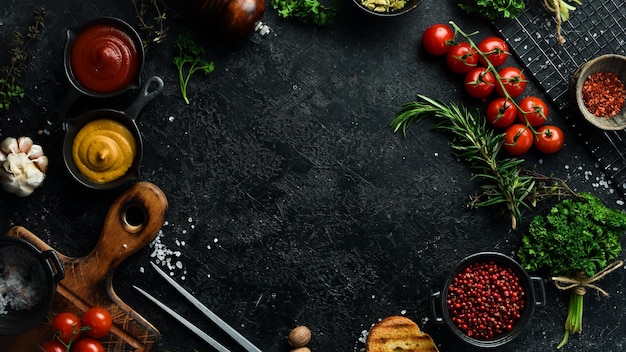 Black stone cooking background Spices and vegetables Top view Free space for your text