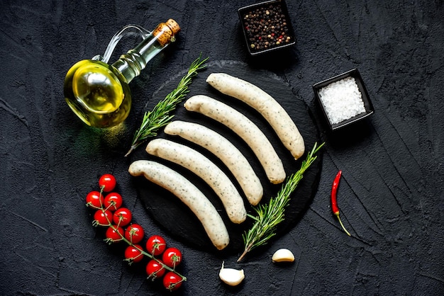 A black stone table with various food items including sausages and olive oil.