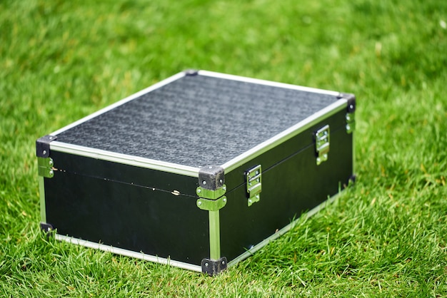 The black suitcase was on green grass. Metal angles and strong hull. magician accessory. there are no people.