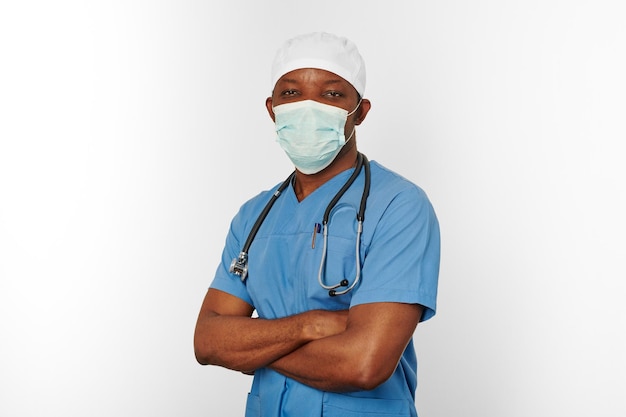 Black surgeon doctor man in blue coat white cap and surgeon mask isolated on white background