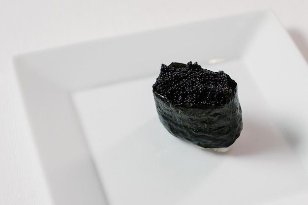 Black sushi maki roll decorated on porcelain plate Copyspace