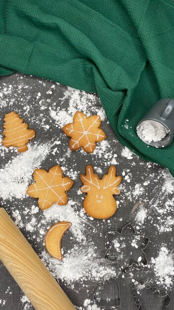 Black table with flour and homemade Christmas cookies Green kitchen towel and rolling pin