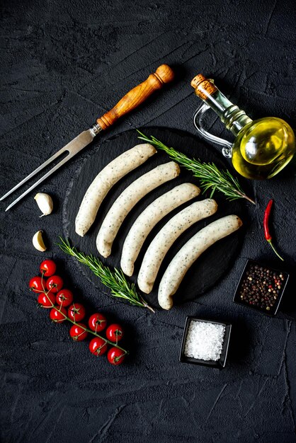 A black table with a knife, a bottle of olive oil, and sausages on it.