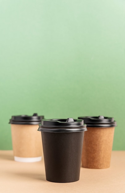 Black takeaway paper coffee cups mock up on green and brown background