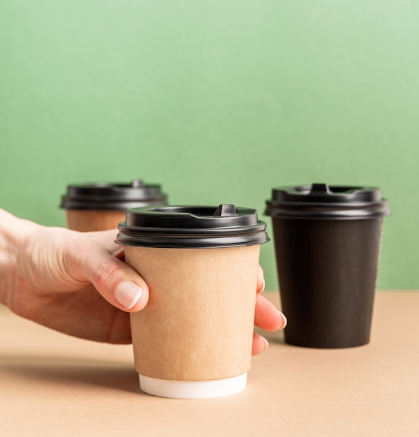 Black takeaway paper coffee cups mock up on green and brown background