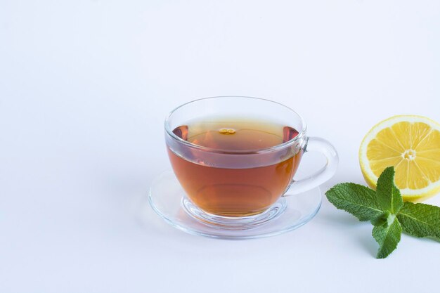 Black tea in the glass cup lemon and mint on the white background Copy space Closeup