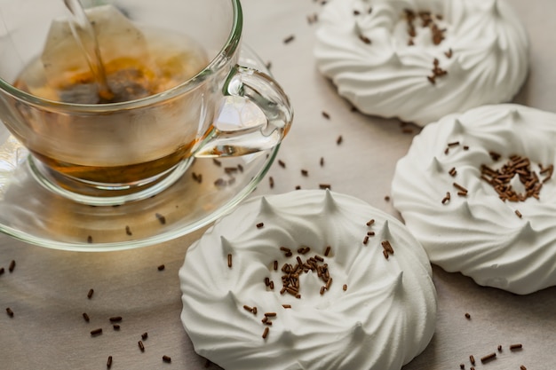 Black tea in transparent cup an air homemade meringues close up