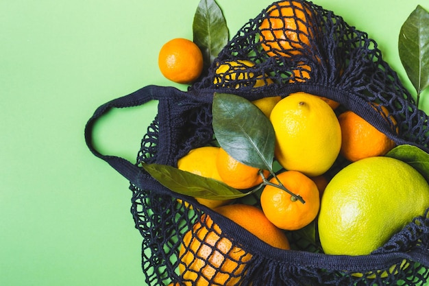 Black textile bag full of colorful citrus fruit. Healthy food and zero waste concept.