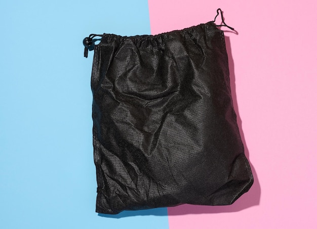 Black textile bag with a rope on a blue pink isolated background