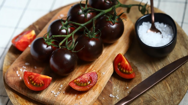 Black tomatoes with sea salt on a wooden board