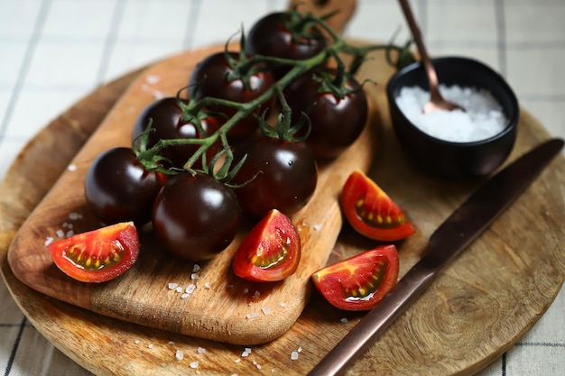 Black tomatoes with sea salt on a wooden board