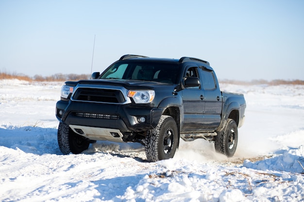 Black truck traveling in the snow