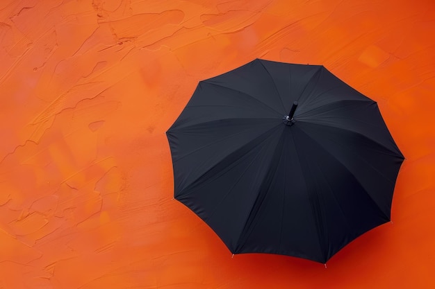 Black umbrella resting against an orange textured wall during daylight