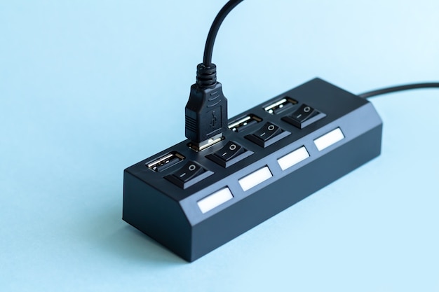 Black USB hub with usb cable plug on light blue surface