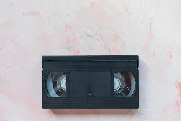 Black vintage VHS video tape on pink background