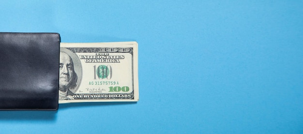 Black wallet with a dollar banknotes on the blue background