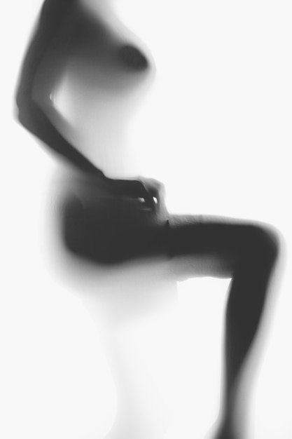 Black and white blurred photo of sexy naked woman putting on nylon stockings