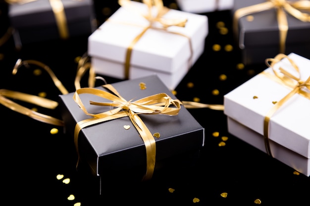 Black and white gift boxes with gold ribbon on shine surface,