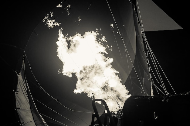 A black and white hot air balloon being hot air filled with flames before sunrise