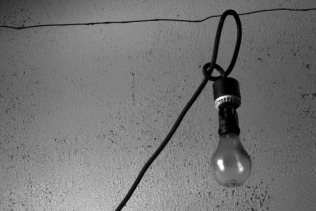 Black and white photo of an exposed lightbulb hanging from a wire