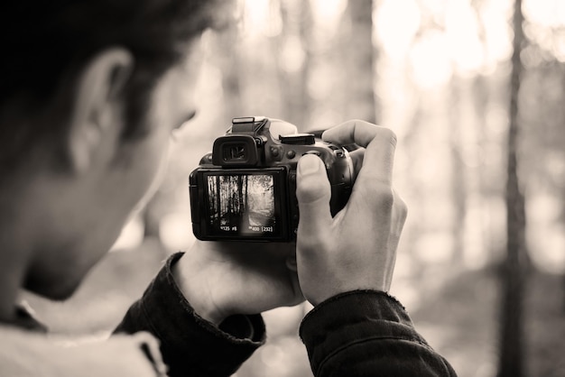 Black and white photo of a male videographer shooting stills and video in the park