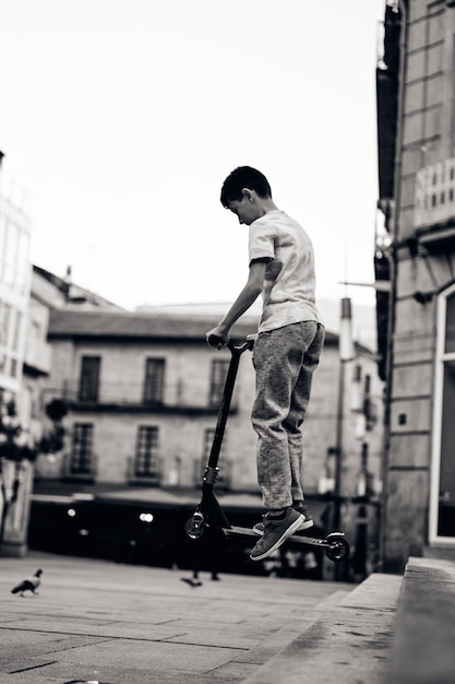 Black and white photo pf a young boy in a scooter stunt