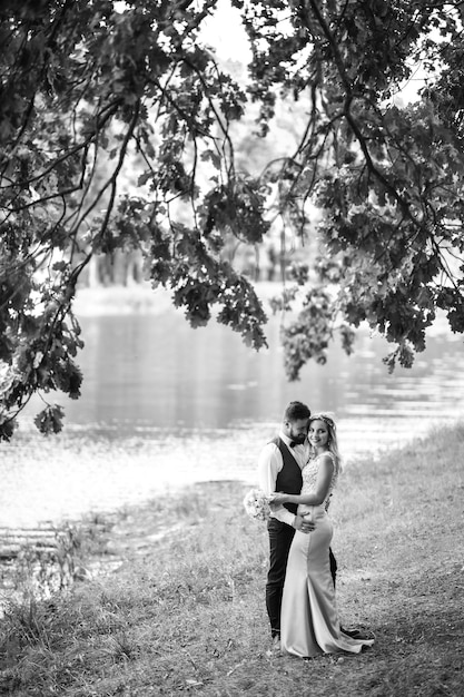 Black and white photo stylish couple of newlyweds posing on a bridge on wedding day