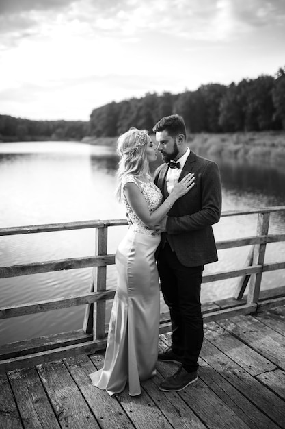 Black and white photo stylish couple of newlyweds posing on a bridge on wedding day