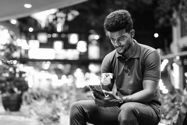 Black and white portrait of handsome black man in city at night