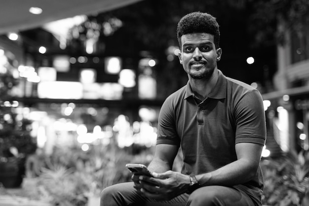 Black and white portrait of handsome black man in city at night