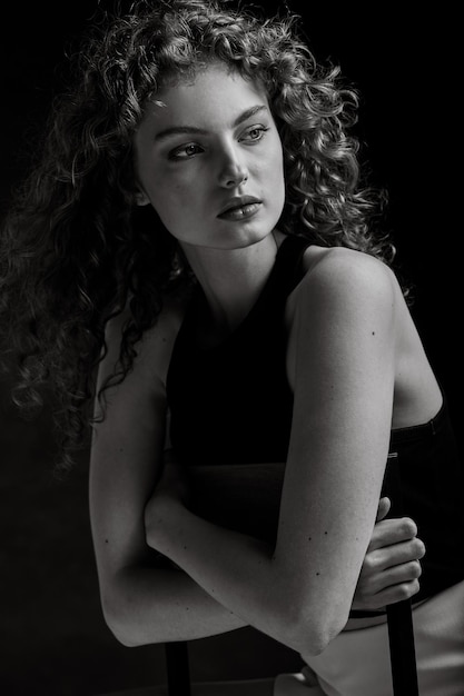 Black and white portrait of a pretty woman sitting on a chair.