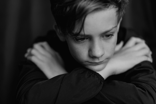 Black and white portrait of teenage boy on dark background Low key close up shot of a young teen boy Black and white photography Selective focus