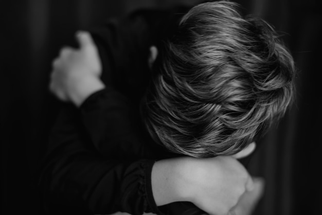 Black and white portrait of teenage boy on dark background Low key close up shot of a young teen boy Black and white photography Selective focus