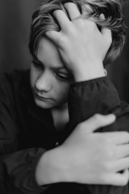 Black and white portrait of teenage boy on dark background Low key close up shot of a young teen boy Black and white photography Selective focus