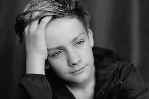 Black and white portrait of teenage boy on dark background Low key close up shot of a young teen boy Black and white photography Selective focus