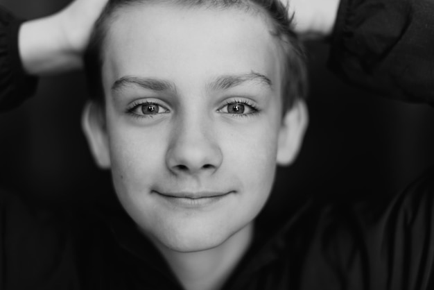 Black and white portrait of teenage boy on dark background Low key close up shot of a young teen boy Black and white photography Selective focus