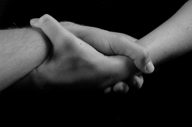 Black and white shot of two hands clasped together at the wrist