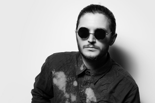 Black and white studio portrait of serious handsome man wearing shades