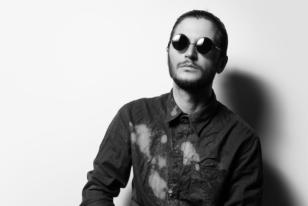 Black and white studio portrait of young attractive man wearing sunglasses