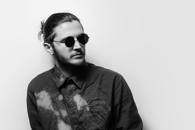 Black and white studio portrait of young handsome man wearing shades