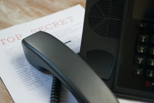 Black wire phone on top of an important document on the table