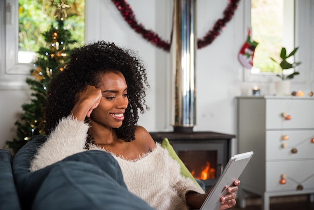 Black woman browsing tablet on couch