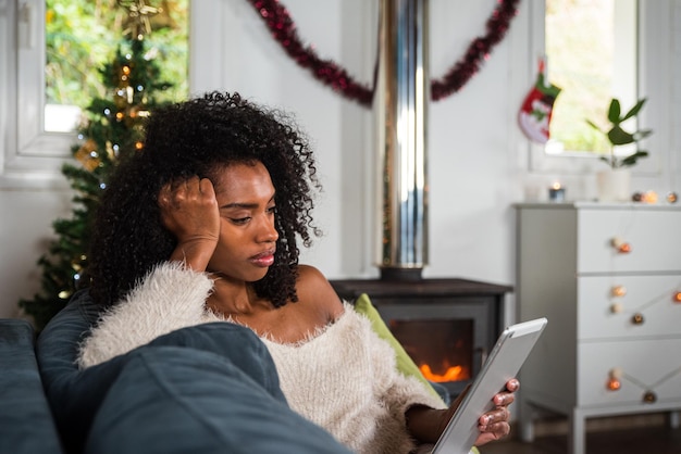 Black woman browsing tablet on couch